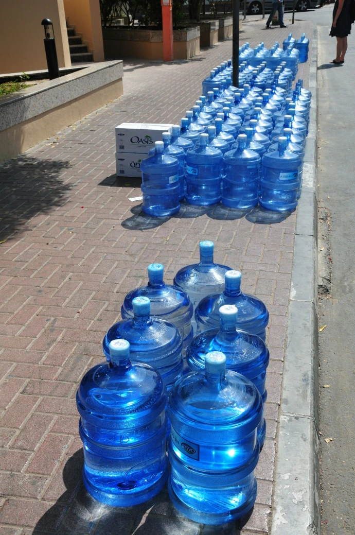 a row of blue water bottles sitting on the side of a road